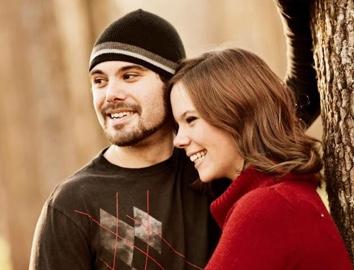 Two people smiling by a tree