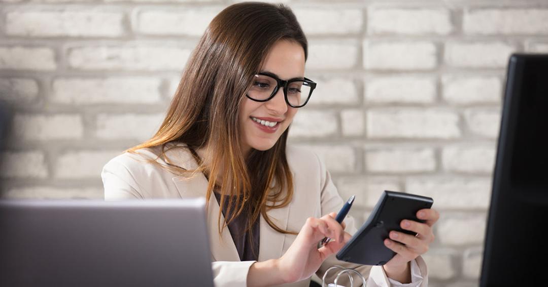 A woman wearing glasses is sitting in front of a computer.